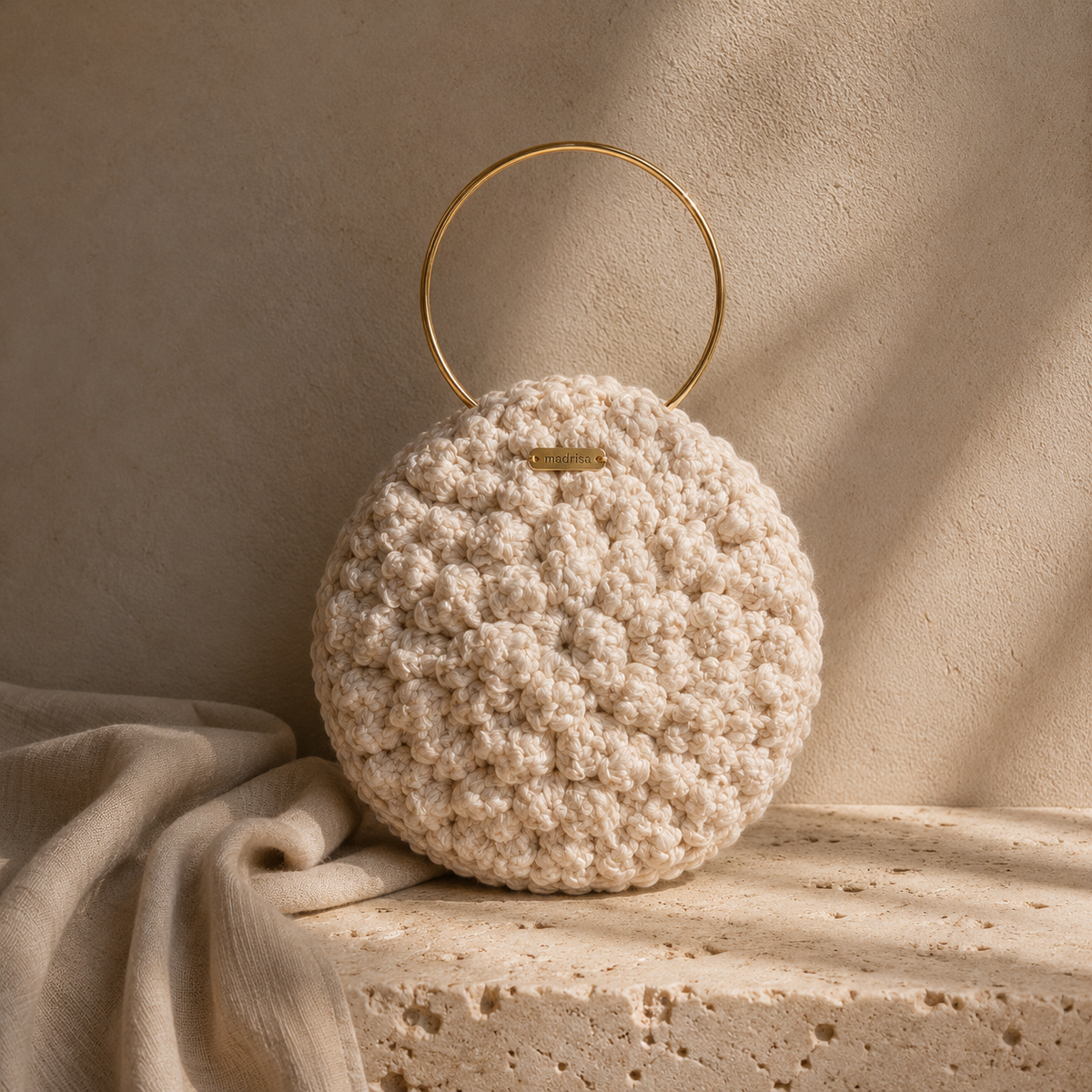Handgemaakte satijnen clutch van Madrista met goudkleurig rond handvat uit de Atelier Collection.